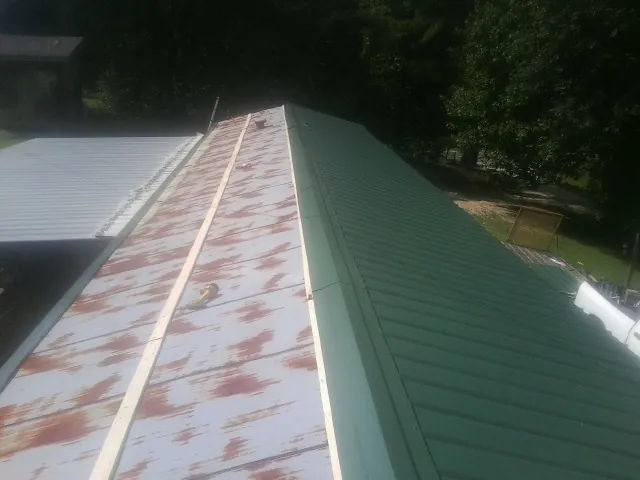 Old rusted panels beside newly installed green metal roofing — Wind Damage Roof Repair by Roofing Brothers in Romeo