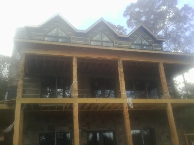 Dormers and porch framing on a large log home under construction — Roof Coating work by our crew in Romeo