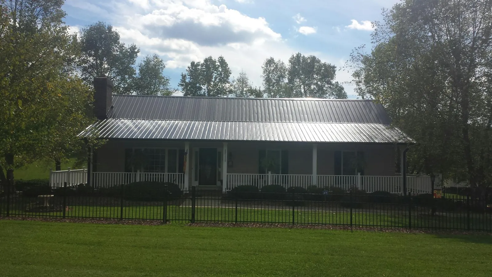 Gray metal roof on a brick ranch with a full width front porch — Gutter Guard Installation work by our crew in Romeo