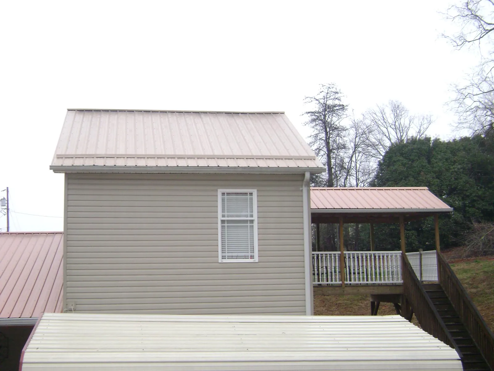 Tan metal roofs on a two story addition and attached porch, from a Roof Replacement job in Romeo
