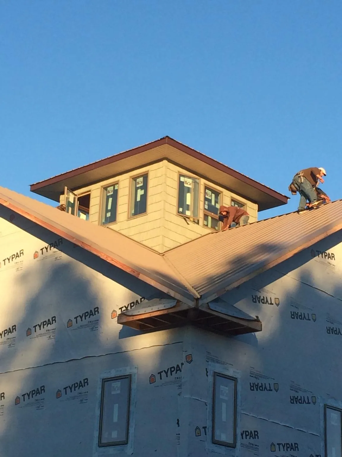 Roofers working around a rooftop cupola on a new metal roof at sunset — Roof Waterproofing in Romeo by Roofing Brothers